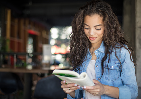 Lost in every page. African American girl at cafe reading book.