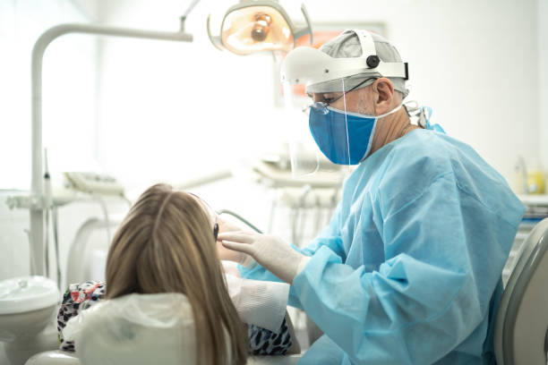 senior dentist examining the teeth of a young woman - dentist office dentists chair dental equipment white imagens e fotografias de stock