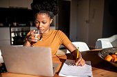 Woman drinking water while she focused on her online lecture