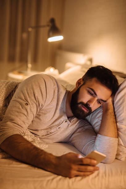 istock Handsome bearded man using phone in the bed at night 1250450648