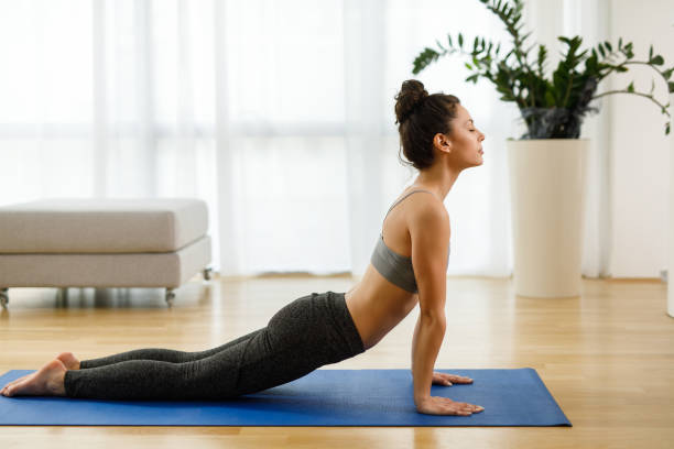 istock Beautiful young woman practicing yoga at home 1250451623