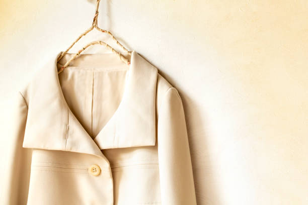 istock beige or white jacket hanging on clothes hanger on white background. 1250453849