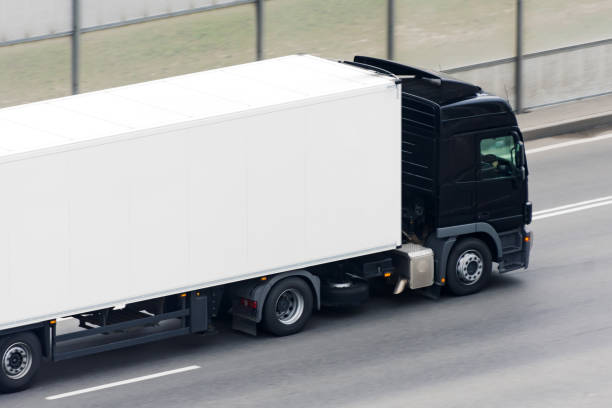 istock Truck with a black cab and a white trailer compartment drives on the highway. 1250454384