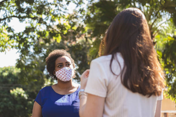 istock Two young women talking and wearing protective face mask. 1250455223