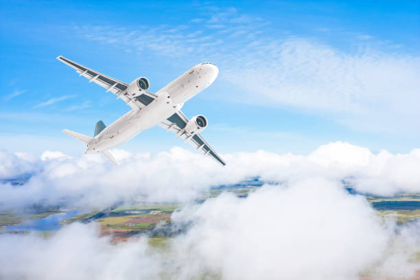 istock A gaining passenger plane flies above the clouds and forest landscape. 1250455973