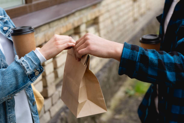istock cropped view of student giving paper bag while holding disposable cup 1250457430