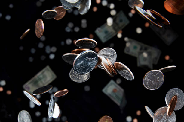 Falling coins reflect the economy and currency Studio shot of falling coins that appear to defy gravity in the air represent the economy and finance with a nickel in focus capitalism stock pictures, royalty-free photos & images