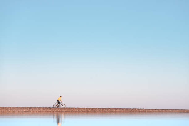 istock A cyclist rides on a stone spit. The view from the water. 1250462879