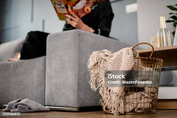 Wicker Basket With Handmade Beige Plaid Inside Standing Near Sofa Stock Photo - Download Image Now