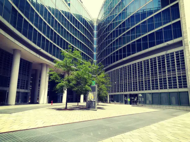 Milan Lombardy palace, blue glass modern city building structure with green tree