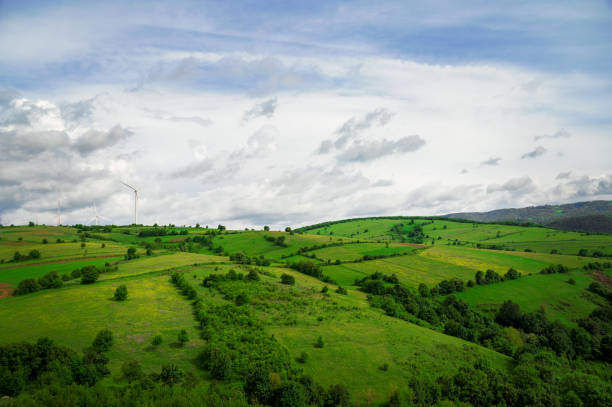 istock Green grass field on small hills and blue sky with clouds 1250469872