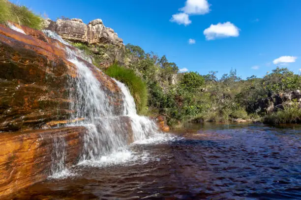 Photo of Sentinela waterfall with small lake and trees around, blue sky, Diamantina, Minas Gerais, Brazil