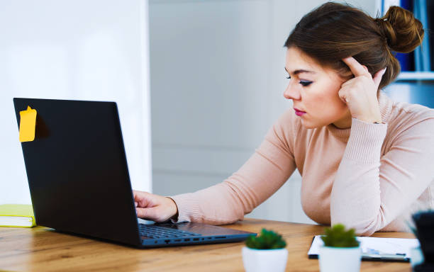 istock Sad office girl typing on laptop in light office 1250470150
