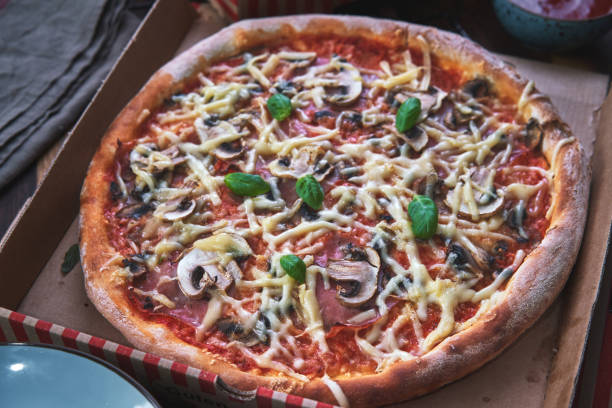 istock Pizza with Prosciutto Ham, Mushroom and Fresh Basil in a Take Away Box 1250470194