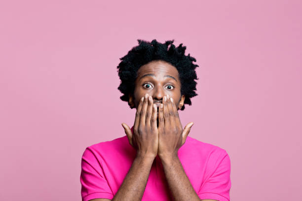 headshot de jovem surpreso vestindo camisa polo rosa - polo shirt african ethnicity men african descent - fotografias e filmes do acervo