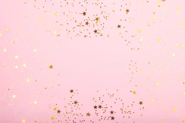 Photo of A bodrer made with falling confetti on pink background.