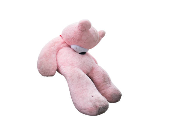 Tired plush big bear sitting isolated on white Dirty sleeping pink plush large toy bear sitting half side view isolated on white pink teddy bear stock pictures, royalty-free photos & images