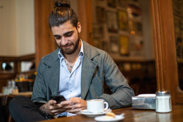 istock Young man sitting at local cafe and using phone 1250476893