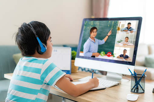 Videoconferencia de niños asiáticos e-learning con profesor y compañeros de clase en la computadora en la sala de estar en casa. Educación en casa y aprendizaje a distancia, en línea, educación e internet. photo