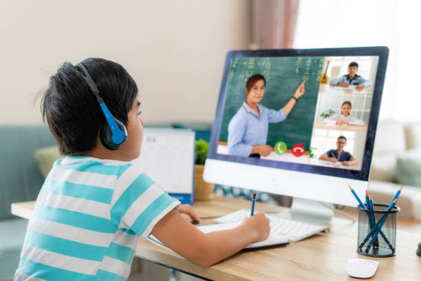 videoconferencia de niños asiáticos e-learning con profesor y compañeros de clase en la computadora en la sala de estar en casa. educación en casa y aprendizaje a distancia, en línea, educación e internet. - educación en el hogar fotografías e imágenes de stock