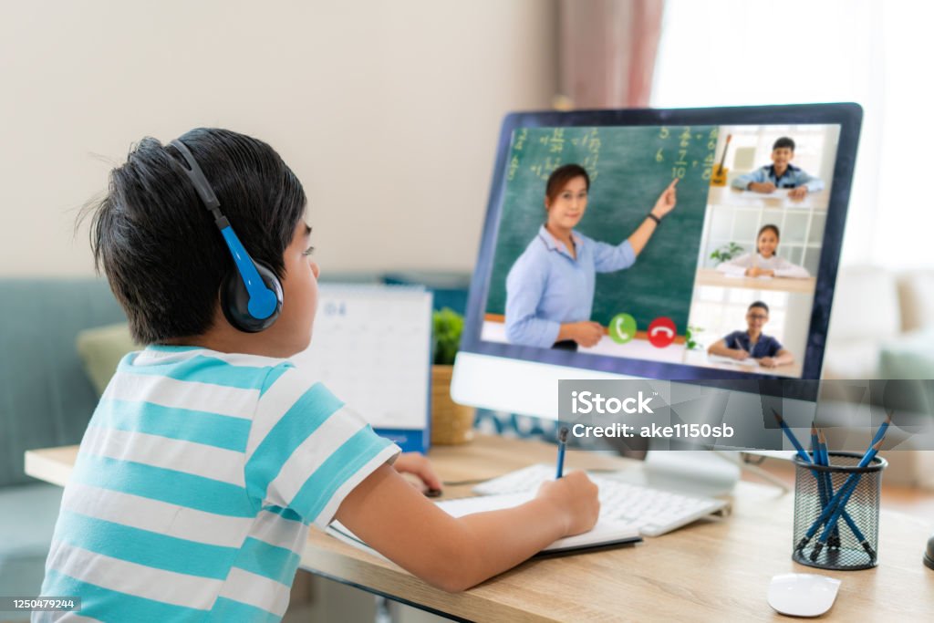 Asian boy student video conference e-learning with teacher and classmates on computer in living room at home. Homeschooling and distance learning ,online ,education and internet. E-Learning Stock Photo