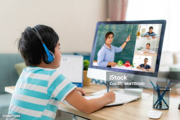 Asian Boy Student Video Conference Elearning With Teacher And Classmates On Computer In Living Room At Home Homeschooling And Distance Learning Online Education And Internet Stock Photo - Download Image Now