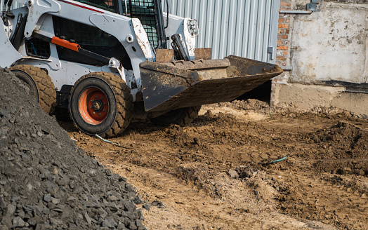 White skid steer loader at a construction site working with a soil. Industrial machinery. Industry