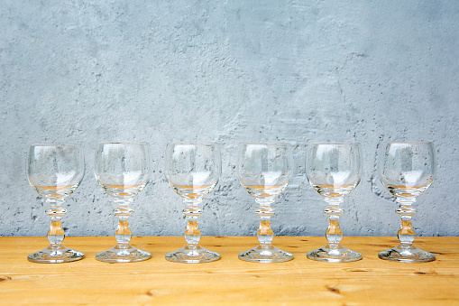 close-up of row of wine glasses on wooden table with grey background