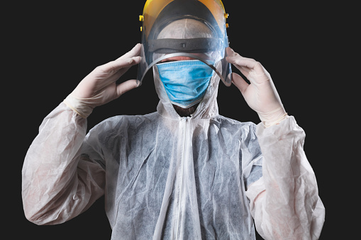 Medical doctor, nurse, surgeon, psychologist working with protective mask, glasses and gloves helping people in the days of panic, pandemic - studio shot on black background.