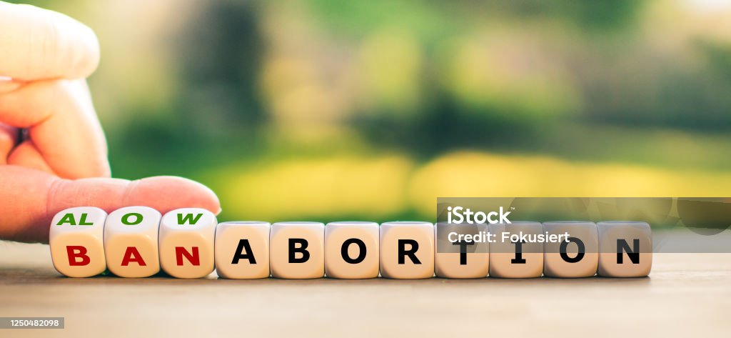 Hand turns dice and changes the expression "ban abortion" to "allow abortion", or vice versa. Abortion Stock Photo