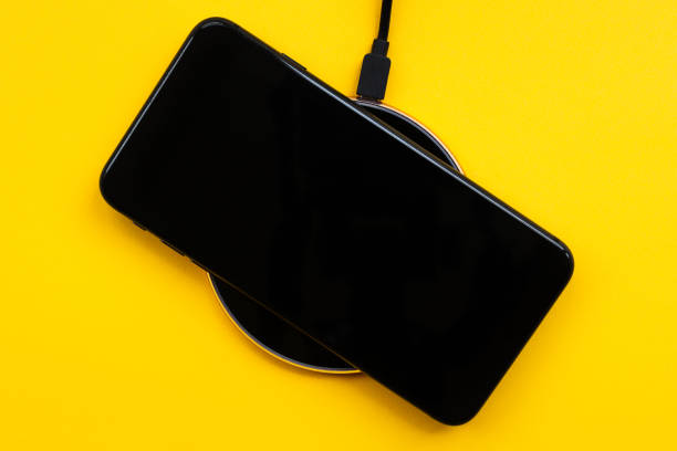 istock The black mobile phone is on wireless charging, on a yellow background. Modern technologies, electronic gadgets. Close-up, flat lay, mock up 1250484921