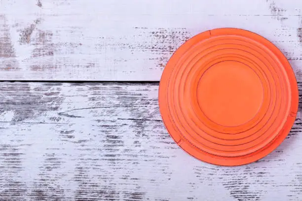 Orange flying target plate against white wooden background