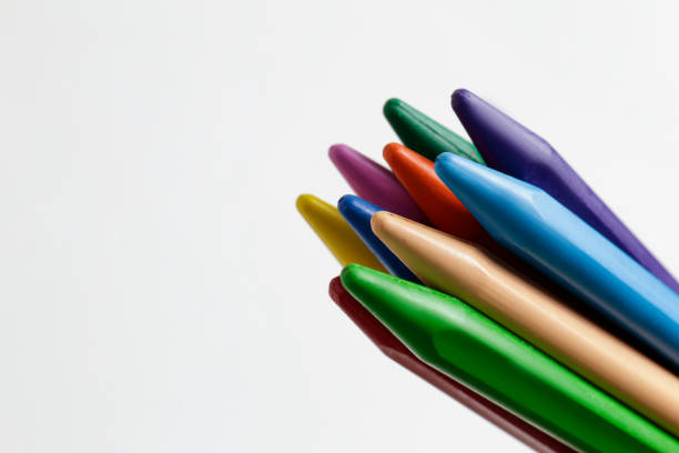 Bunch of different colorful wax crayon pencils laid oun in composition, isolated on white. Soft pastel for drawing in stack. Close up, copy space, top view.