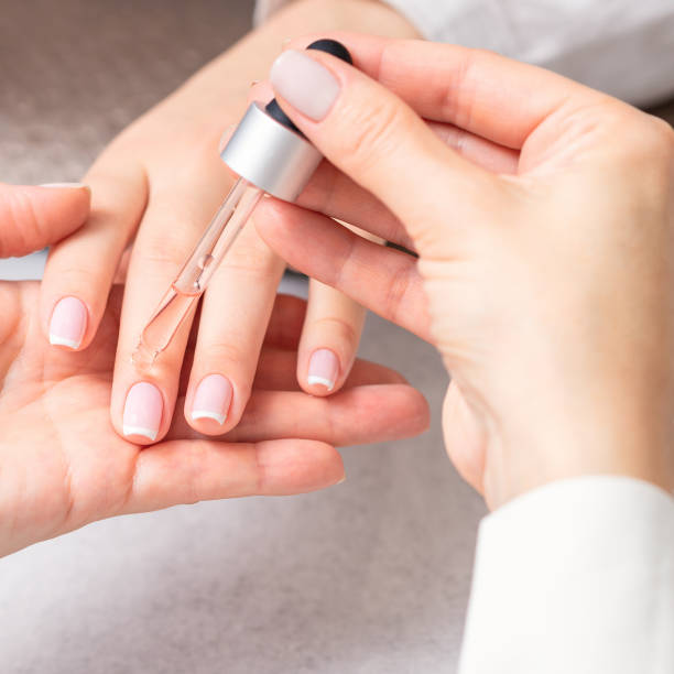 Manicurist pours oil on nails of woman Professional manicurist pouring oil on nails french manicure of woman in beauty salon. cuticle photos stock pictures, royalty-free photos & images