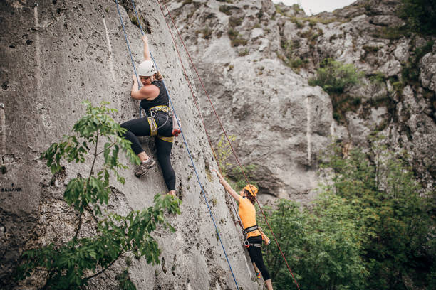 istock Women free climbers climbing high 1250490871