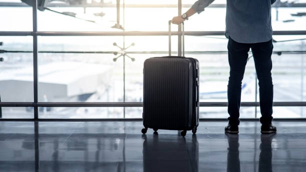 Tourist man holding suitcase luggage in airport Vacation trip or travel abroad concept. Immigration and baggage claim. Tourist man holding suitcase luggage waiting for airline flight check-in at international airport terminal. wheeled luggage stock pictures, royalty-free photos & images