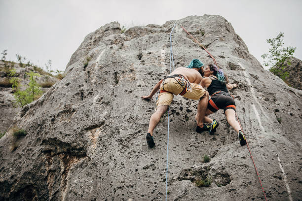 Man and woman, free climbers, climbing on the rock mountain in nature.