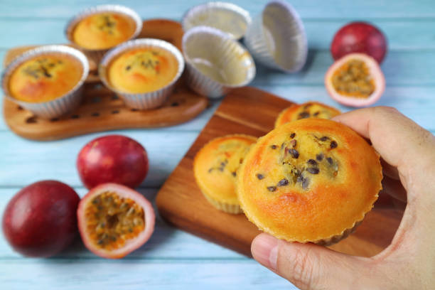 Closeup Fresh Baked Homemade Passion Fruit Muffins in Hand against Blurry Messy Kitchen Table