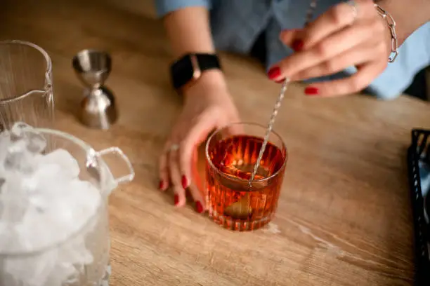 Photo of view of glass with brown drink which woman stirs with spoon