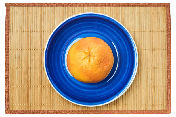 istock rosy yellow grapefruit on a blue plate on a cane place mat 1250499122