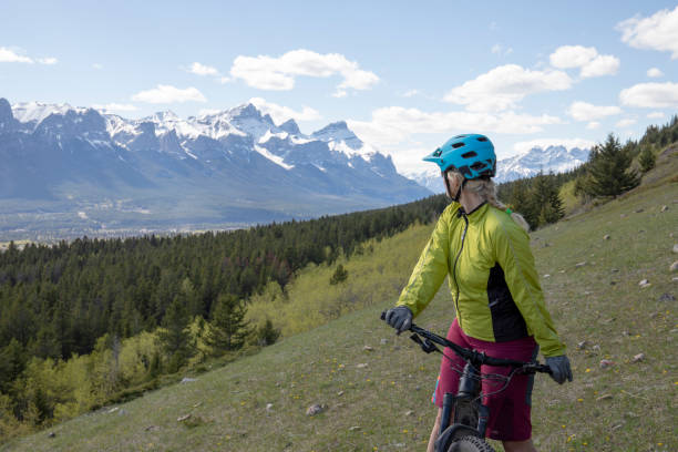 istock Female mountain e-biker rides along grassy slope 1250499304