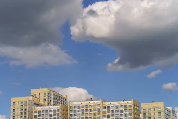 White and gray clouds over the residential buildings in the Moscow spring sky. Modern buildings. Concepts of lifestyle and beauty of nature. Telephoto lens.