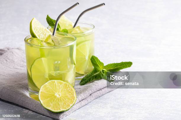 Two Glasses With Iced Green Matcha Tea With Lime Ice Fresh Mint And Metal Drinking Straws On Light Grey Backdrop Stock Photo - Download Image Now