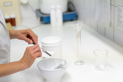 A close up view of a pharmacist in the laboratory mixing a medical ointment in a bowl