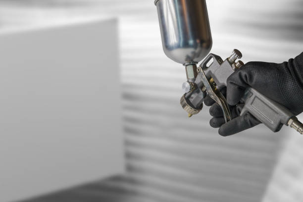 Male hand holding painter spray gun.