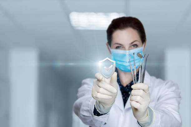 Doctor dentist shows a tool and and a guarantee of quality work on a blurred background.