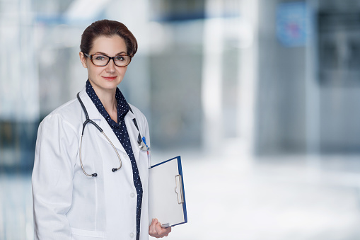 Doctor with glasses and a check sheet in hand on a blurred background.