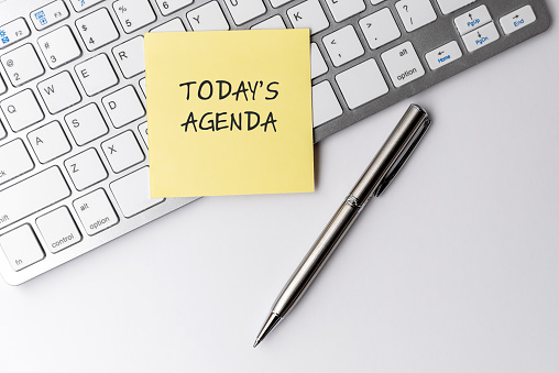 Today's agenda text on sticky note with computer keyboard and pen