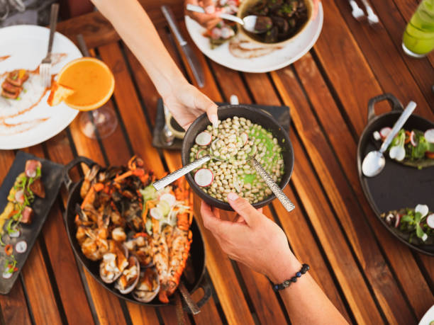 istock Two Hands Passing a Dish Across a Wood Table 1250517480