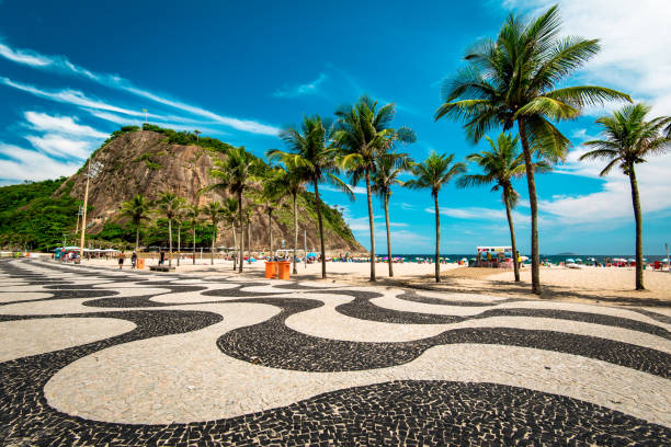 Copacabana Sidewalk Mosaic and Palm Trees in Rio de Janeiro Rio de Janeiro, Brazil - January 27, 2017: Famous mosaic of sidewalk in Copacabana beach, palm trees and the Leme mountain. copacabana stock pictures, royalty-free photos & images